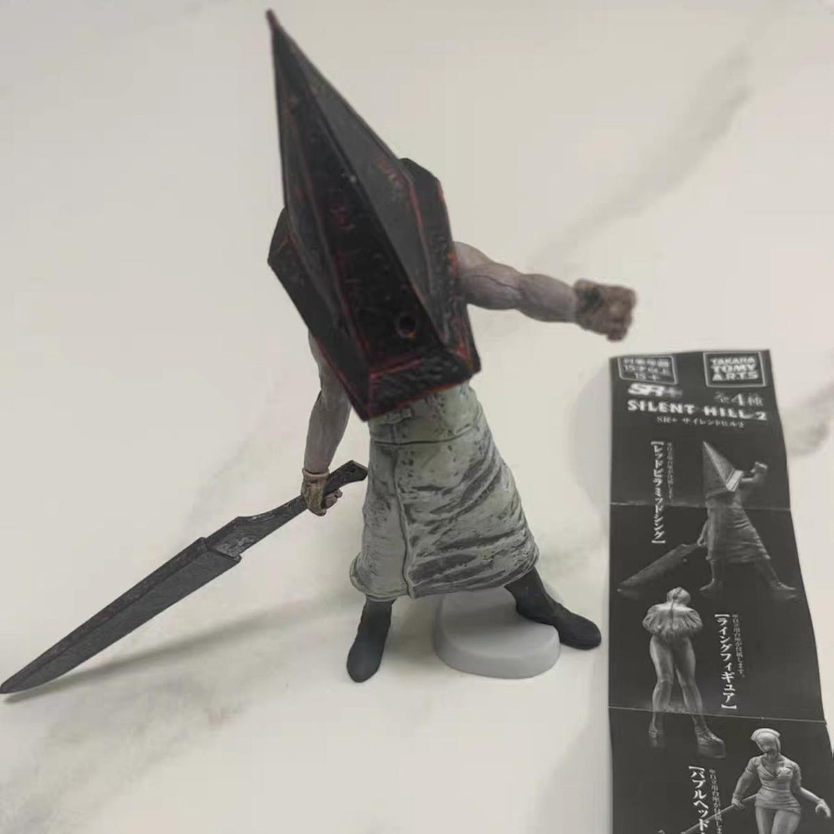 Pyramid-helm figure close-up with paper card