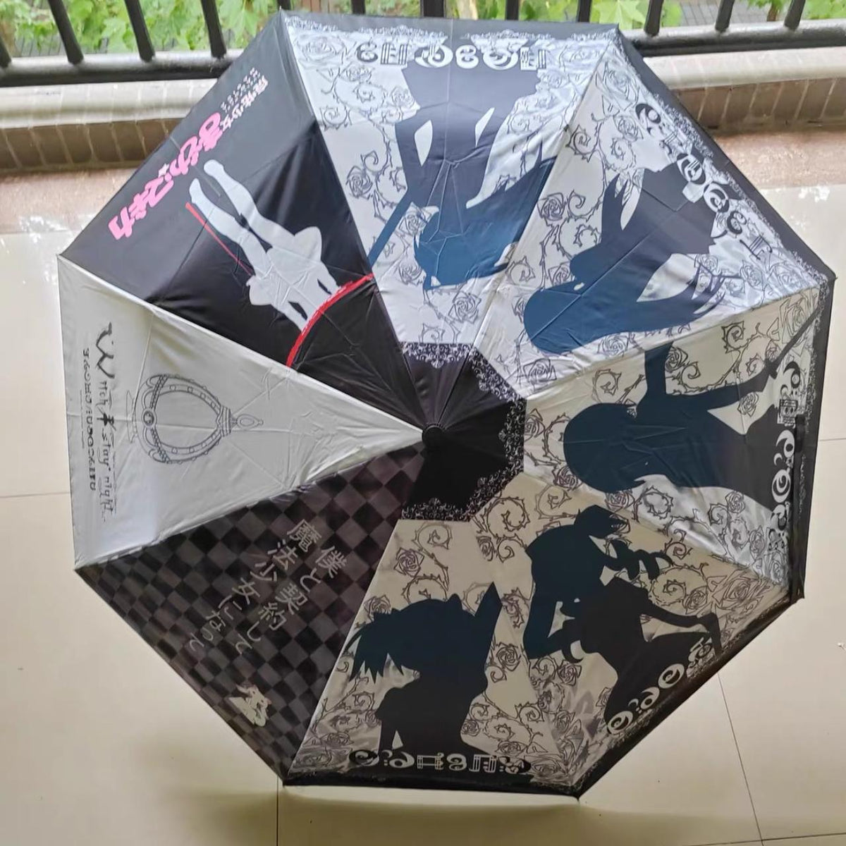 Puella Magi Madoka Magica umbrella opened — black and white gothic rose canopy with Tomoe Mami silhouette panels and Witch stay night crest print