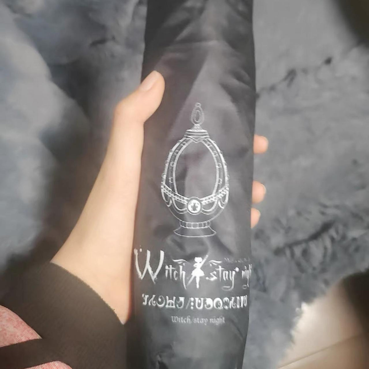 Madoka Magica folding umbrella in its matching black printed carry pouch, held in hand for scale