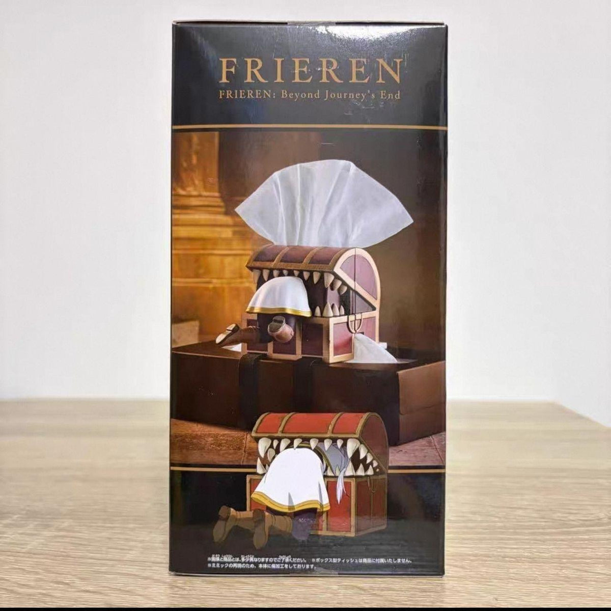 Side of the Frieren tissue box retail packaging showing the chest in use from two angles, the figure crawling under the lid